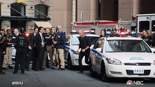 a group of police officers are standing in front of a new york police vehicle
