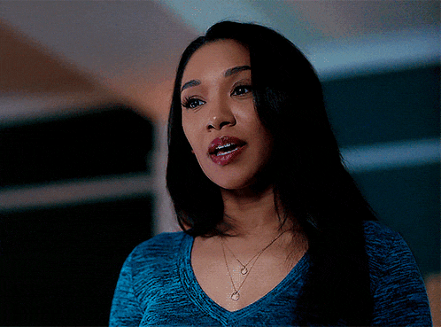 a woman wearing a blue shirt and a necklace with a heart on it