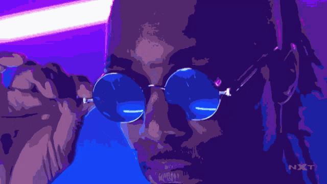 a man wearing a pair of blue sunglasses with the word nxt on the bottom right