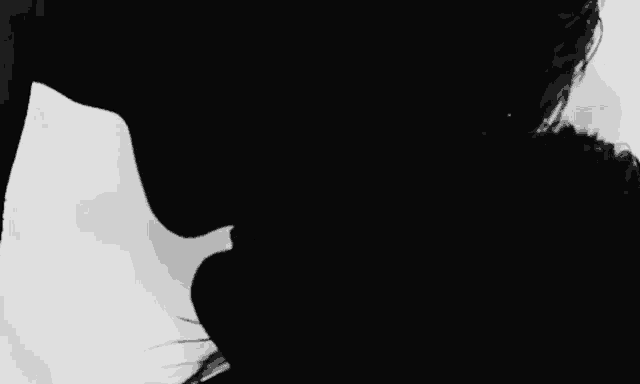 a black and white photo of a man and a woman kissing .