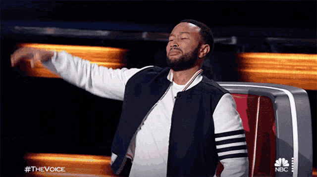 a man with his arms outstretched on a nbc show called the voice