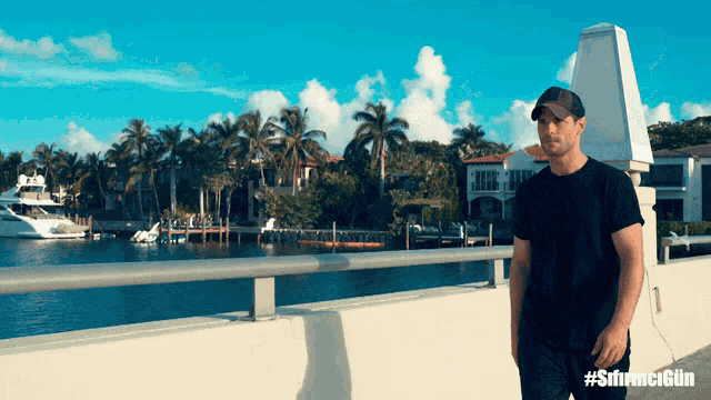 a man in a black shirt stands on a bridge overlooking a body of water with the hashtag #sfirmcgün