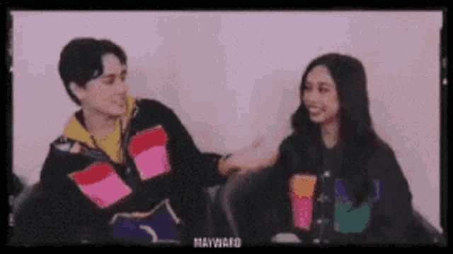 a man and a woman are sitting next to each other in a room .