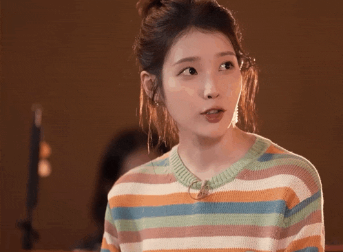 a woman wearing a colorful striped sweater is looking at the camera