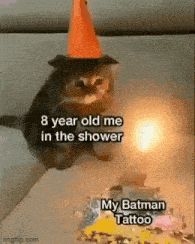 a cat wearing a party hat is sitting in front of a cake with a candle .