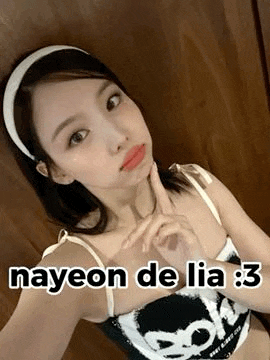 a woman wearing a headband is taking a selfie with her finger on her chin .