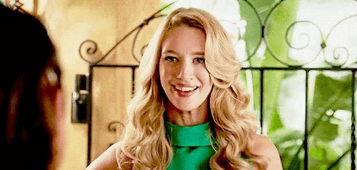 a blonde woman in a green dress is smiling at another woman .