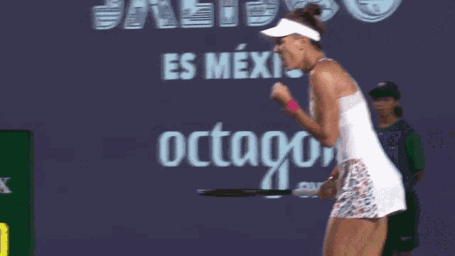 a woman holding a tennis racquet in front of a sign that says octago