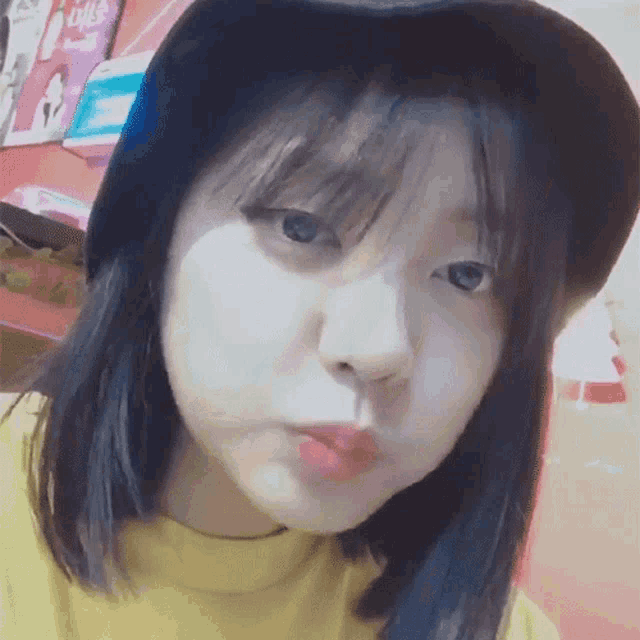 a girl wearing a hat and a yellow shirt is making a face