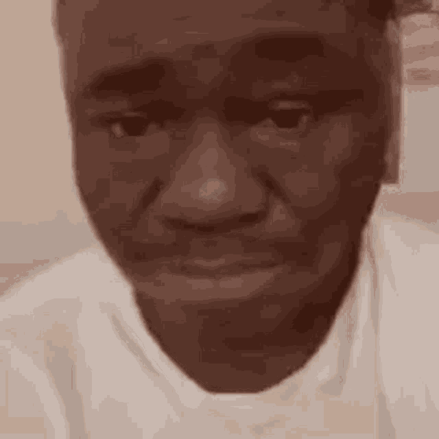 a close up of a man 's face with a white shirt on making a funny face .