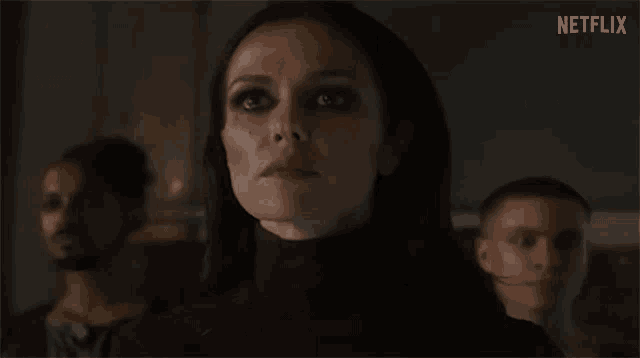 a woman in a black turtleneck is standing in front of a group of men .