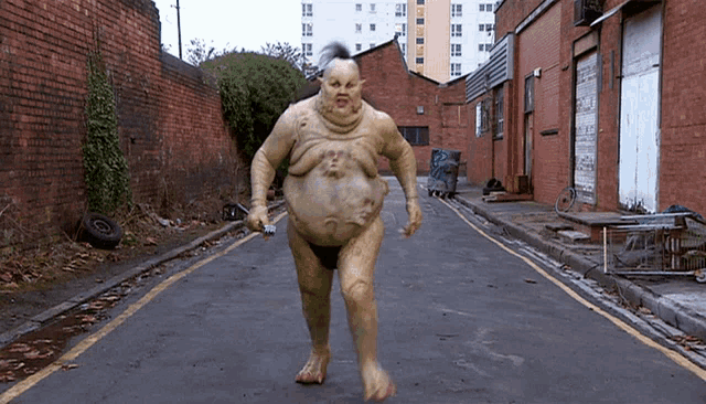 a man with a very large belly is walking down a road