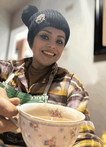 a woman in a plaid shirt is holding a cup of coffee