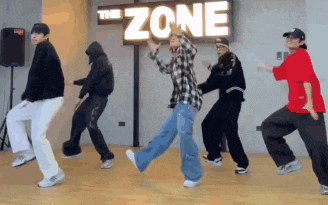a group of young people are dancing in front of a sign that says the zone