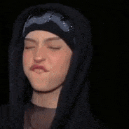 a woman wearing a black hoodie and a black hat is making a funny face .