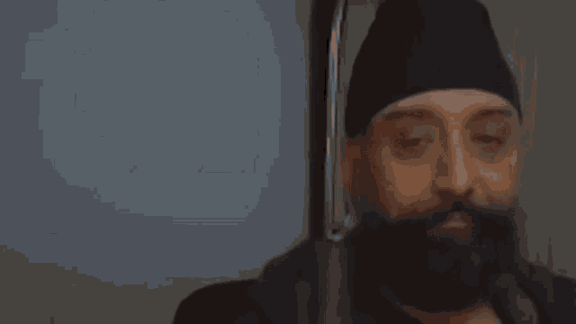 a man with a beard and a hat is making a funny face .