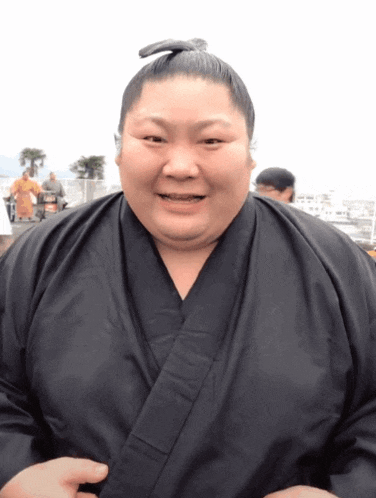 a man in a black kimono with a bun on his head