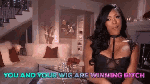 a woman is sitting in a living room with the words " you and your wig are winning bitch " behind her