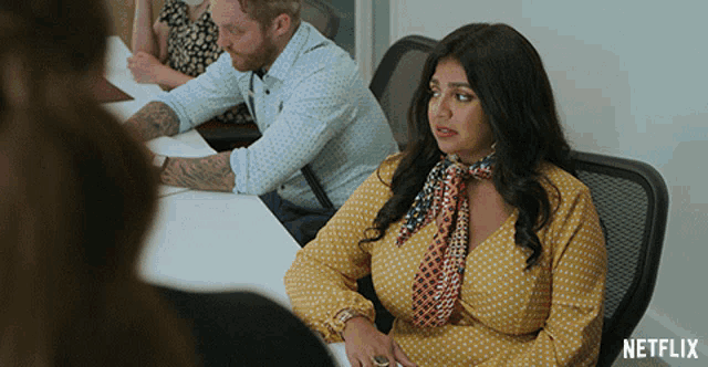 a woman in a yellow polka dot dress sits in a chair with a netflix logo on the bottom