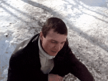 a man wearing a black jacket and a white sweater is standing in the snow