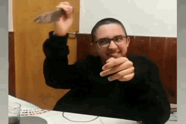 a man is sitting at a table holding a knife .