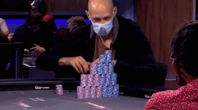 a man wearing a mask is stacking poker chips at a table