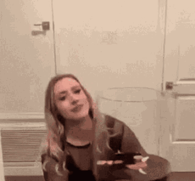 a woman is sitting on a toilet in a room holding a cell phone .