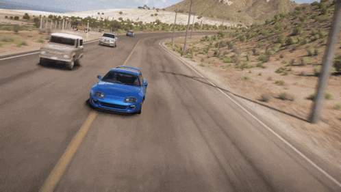 a blue car with a spoiler on the back is driving down the road