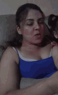 a woman in a blue tank top sits on a couch