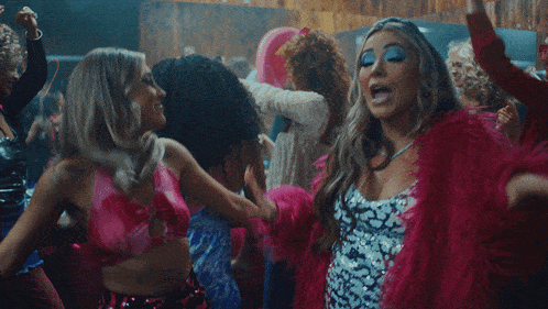 a woman in a pink crop top is dancing with other women