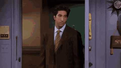 a man in a suit and tie is opening a door .