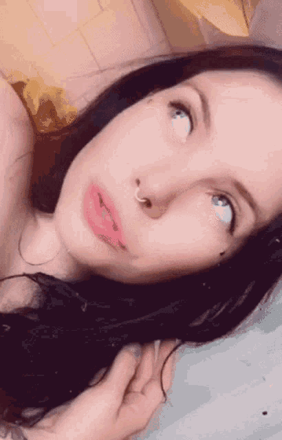 a woman with a nose ring is looking up at something