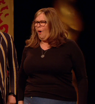 a woman wearing glasses and a black shirt is standing in front of a man .