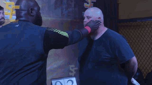two men shaking hands in front of a sign that says slap fight