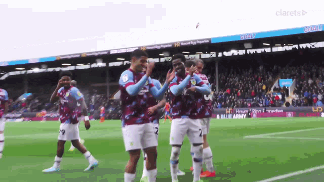 a group of soccer players are celebrating a goal on a field with a sign that says clarets