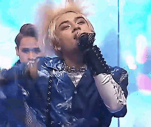 a woman is singing into a microphone while wearing a blue jacket .