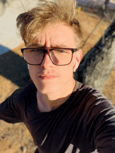 a young man wearing glasses looks at the camera