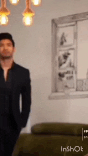 a man in a suit is standing in a living room in front of a window .