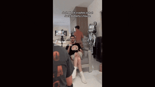 a man wearing a black reload t-shirt stands in front of a basketball hoop