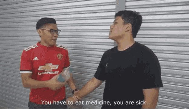 a man wearing a red chevrolet shirt talks to another man