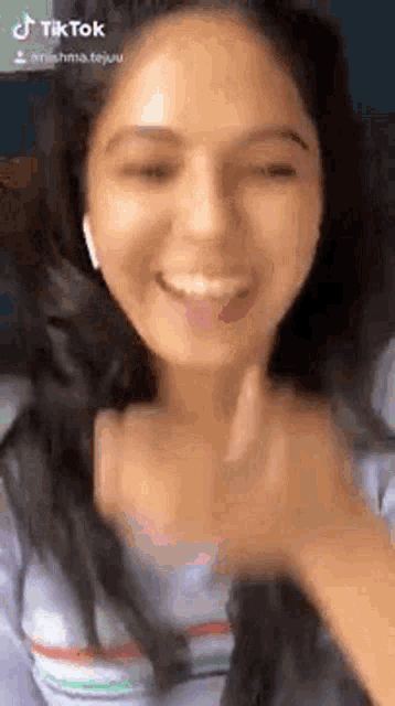 a woman wearing headphones and a striped shirt is smiling and making a funny face .