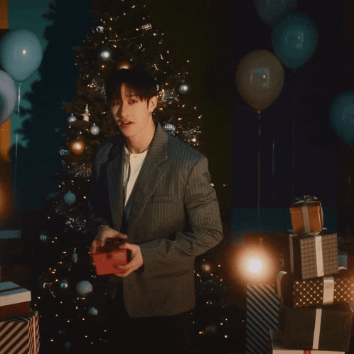 a man in a suit takes a picture of a christmas tree