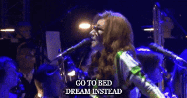 a woman singing into a microphone with the words go to bed dream instead on the bottom