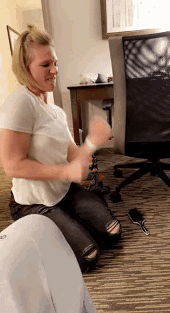 a woman in a white shirt and black jeans is kneeling on the floor