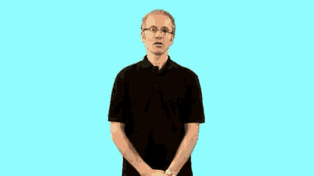 a man wearing glasses and a black shirt is standing in front of a blue background and making a funny face .