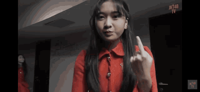 a girl in a red sweater is giving the middle finger to the camera