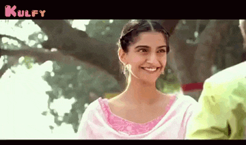 a woman in a pink dress is smiling while standing next to a tree .