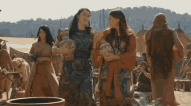 two women are standing next to each other holding vases in front of a crowd .