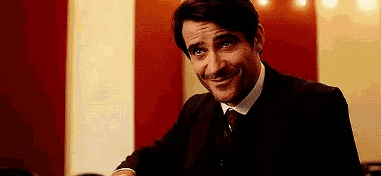 a man in a suit and tie is smiling and leaning on a bar .