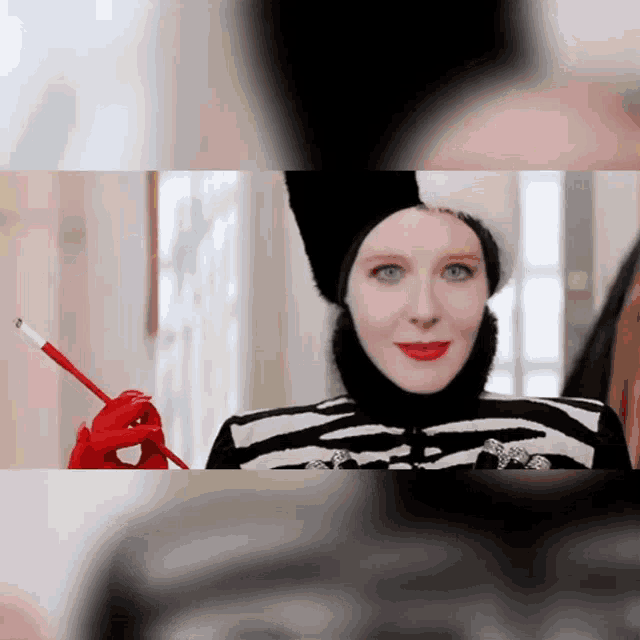 a woman wearing a black hat and red gloves is holding a cigarette
